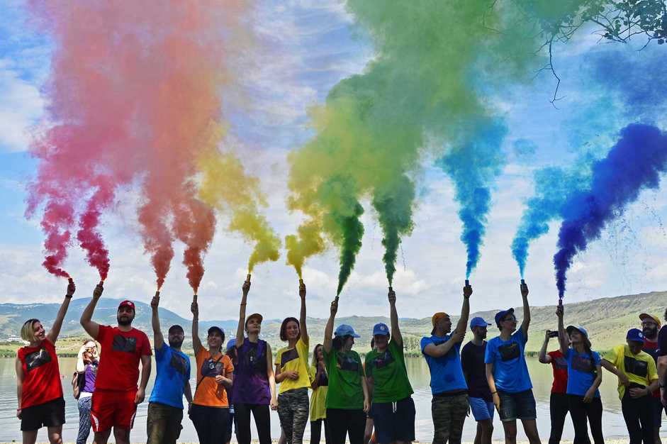 Participants wearing rainbow clothes and shooting rainbow smoke into the air