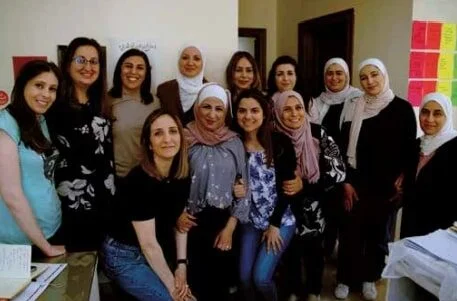 group of Arab women hugging and smiling at the camera