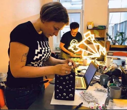 woman sewing google eye onto a purse